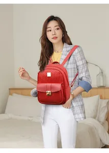Detail of red embossed PU leather backpack with gold buckle and fuzzy charm