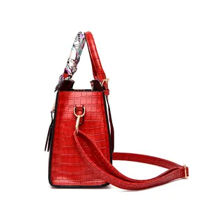 Detail of red crocodile pattern handbag with elegant silk scarf and gold-tone hardware