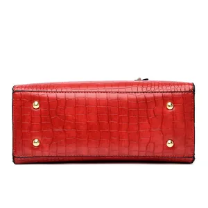 Bottom view of red crocodile texture handbag showing four golden protective metal studs