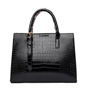 Close-up of black crocodile pattern leather handbag with colorful silk scarf on handle