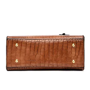 Brown crocodile embossed handbag bottom featuring protective gold studs and clean edges