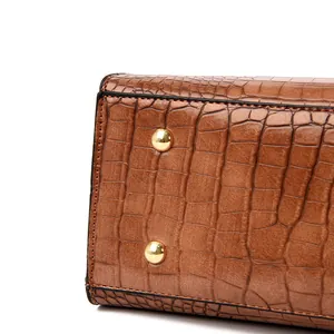 Close-up of brown crocodile pattern leather handbag base with gold metal feet