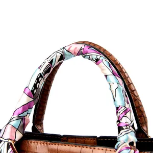 Close-up of brown crocodile embossed leather handbag handle wrapped with a colorful silk scarf
