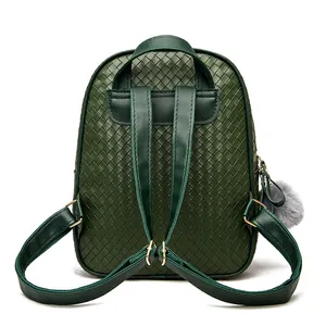 Detail view of dark green PU leather backpack with woven pattern and grey pompom charm