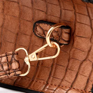 Detailed close-up of golden metal hooks and crocodile pattern leather on a brown handbag
