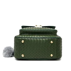 Detail of green woven PU leather backpack base with gold metal protective feet and gray pompom