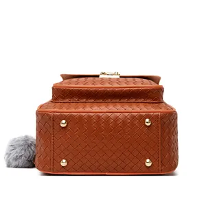 Detail of brown woven PU leather backpack with gold bottom studs and plush charm