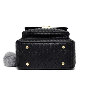 Detail view of woven black backpack base with gold metal protective feet and fur charm