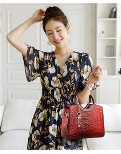 Close-up of crocodile pattern handbag with gold rivet details and key charm