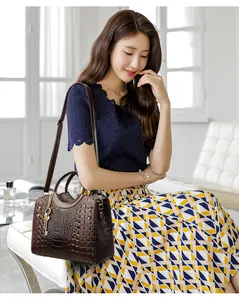 Close-up of brown crocodile pattern tote featuring gold key charm and rivet details