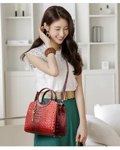 Close-up of wine red crocodile pattern handbag with metal handles and key charm