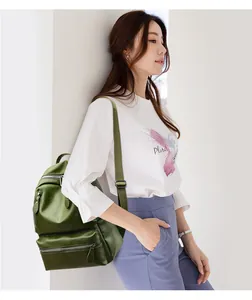 Deep green glossy leather backpack shown from the side on a model against a white wall
