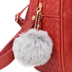 Detail of red woven faux leather backpack with a grey faux fur pompom keychain