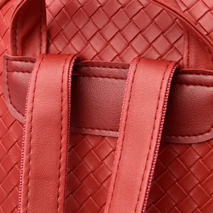 Detailed close-up of wine red woven leather straps and reinforced stitching on a backpack