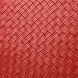 Macro shot of red PU leather with intricate woven Intrecciato pattern and matte finish