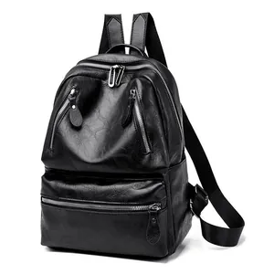 Detail of black faux leather backpack featuring pebble texture and multi-zipper pockets