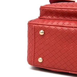 Detail of red woven PU leather backpack showing texture and golden protective metal feet