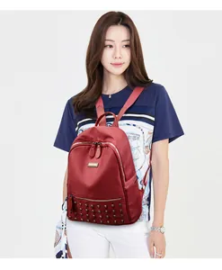 Detail of red nylon backpack with stylish square metal rivets and a textured finish
