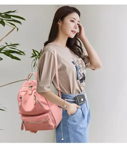 Vue détaillée d'un sac à dos rose en nylon avec plusieurs poches et bretelles tissées
