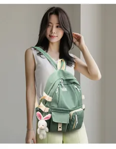 Close-up of Morandi green multi-pocket nylon backpack with cute white rabbit pendant