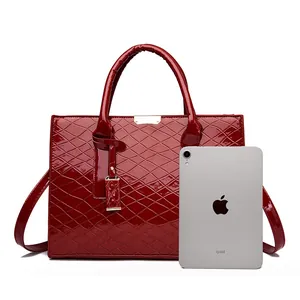 Dunkelrote Lackleder-Handtasche mit Rautensteppung neben einem iPad zum Größenvergleich