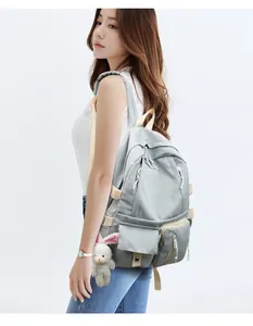 Light gray nylon backpack detail showing side pockets and white plush bunny charm