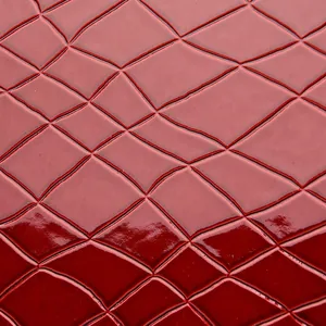 Makroaufnahme von dunkelrotem Leder mit Krokodilprägung und glänzendem Finish