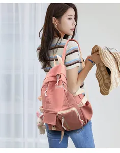 Detail showing the coral pink nylon backpack with adjustable straps and cute rabbit charm