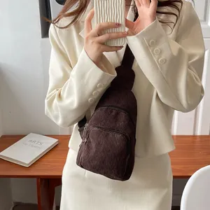 Detailed macro view of dark brown corduroy chest bag featuring dual zipper compartments