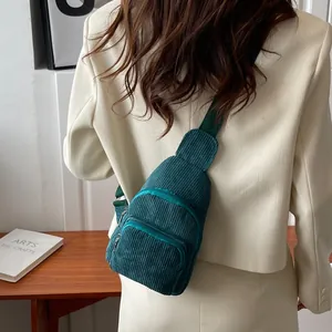 Detail of dark green corduroy sling bag showing striped texture and silver hardware