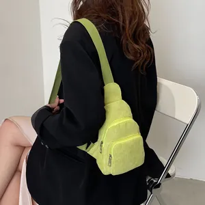 Detail view of lime green corduroy chest bag with textured vertical stripes and dual zippers