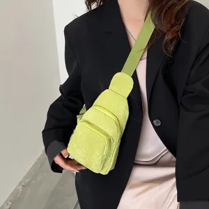 Detail showing a light green corduroy crossbody bag worn over a black blazer for a casual look
