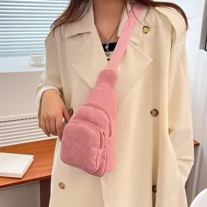 Detailed macro of pink corduroy chest bag with dual zippers and fabric shoulder strap