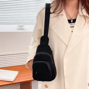 Detail of black corduroy chest bag featuring multiple zipper pockets and wide strap