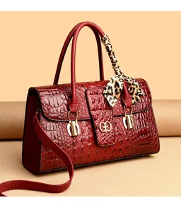 Detail of dark red crocodile embossed handbag with gold logo and leopard print silk scarf