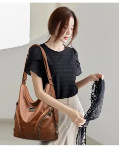 Detailed view of brown PU leather shoulder bag featuring stud accents and side zippers
