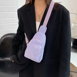 Detailed view of light purple corduroy crossbody bag worn over a black blazer