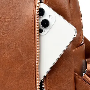 Detail view of the brown PU leather backpack with a functional side zipper pocket