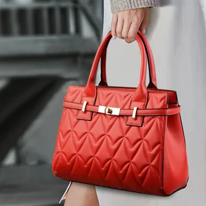 Borsa a mano rossa trapuntata con motivo a cuore e chiusura dorata tenuta da modella