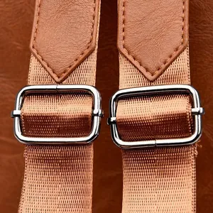 Close-up of brown PU leather backpack straps with silver metal adjustment buckles