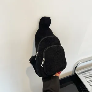 Detailed view of black corduroy waist bag showing ribbed texture and metal zippers