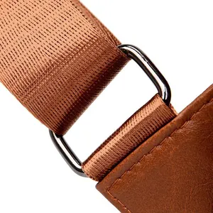 Detail of brown PU leather bag with woven nylon strap and black metal hardware
