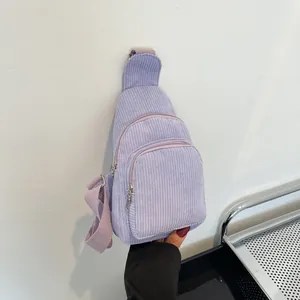 Detail of lavender corduroy chest bag featuring dual zipper pockets and woven strap