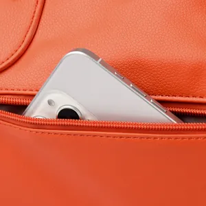 Dettaglio borsa in pelle arancione con tasca posteriore con zip funzionale e uno smartphone