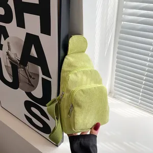 Detail of light green corduroy crossbody bag with multiple zipper pockets and strap