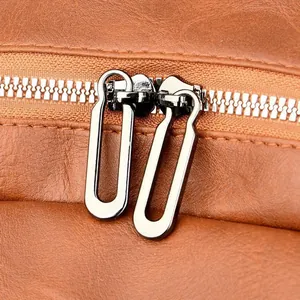 Close-up of dual silver zippers and textured brown faux leather on a retro backpack