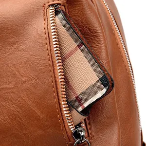 Detail of brown PU leather bag showing metal zipper and classic plaid fabric lining