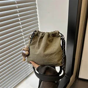 Borsa a secchiello in nylon verde militare con ciondolo di peluche e tracolla regolabile