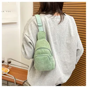 Close-up of light green corduroy chest bag showing vertical texture and zipper details