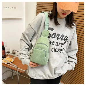 Detail of light green corduroy chest bag featuring adjustable strap on casual outfit